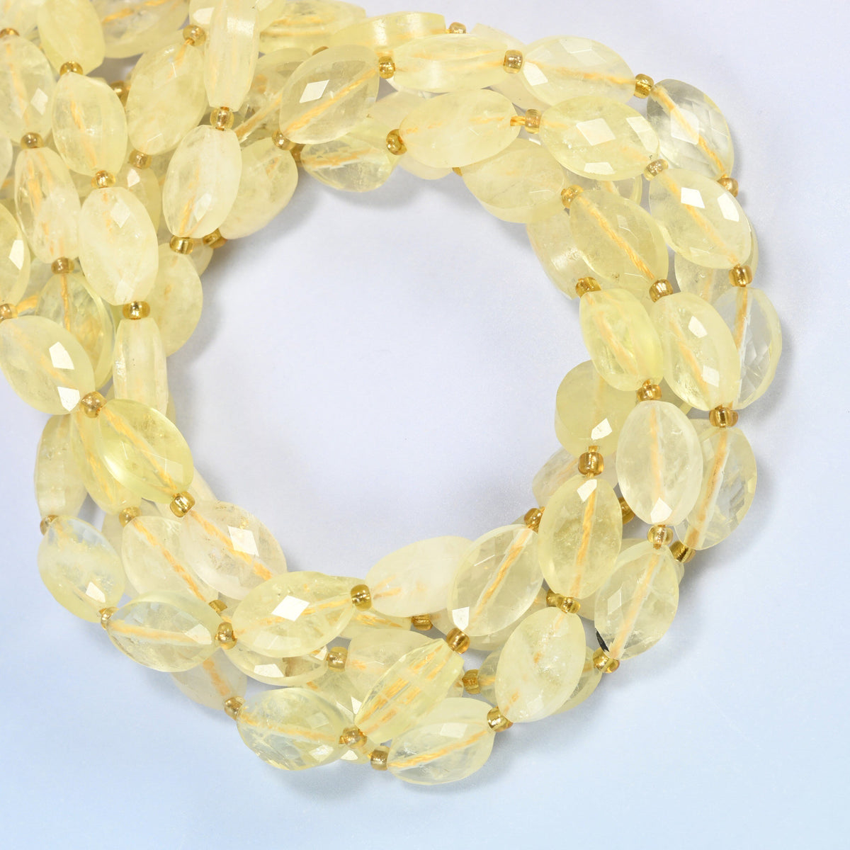 Citrine faceted flat oval beads coiled into overlapping loops, whole strands of soft yellow stone