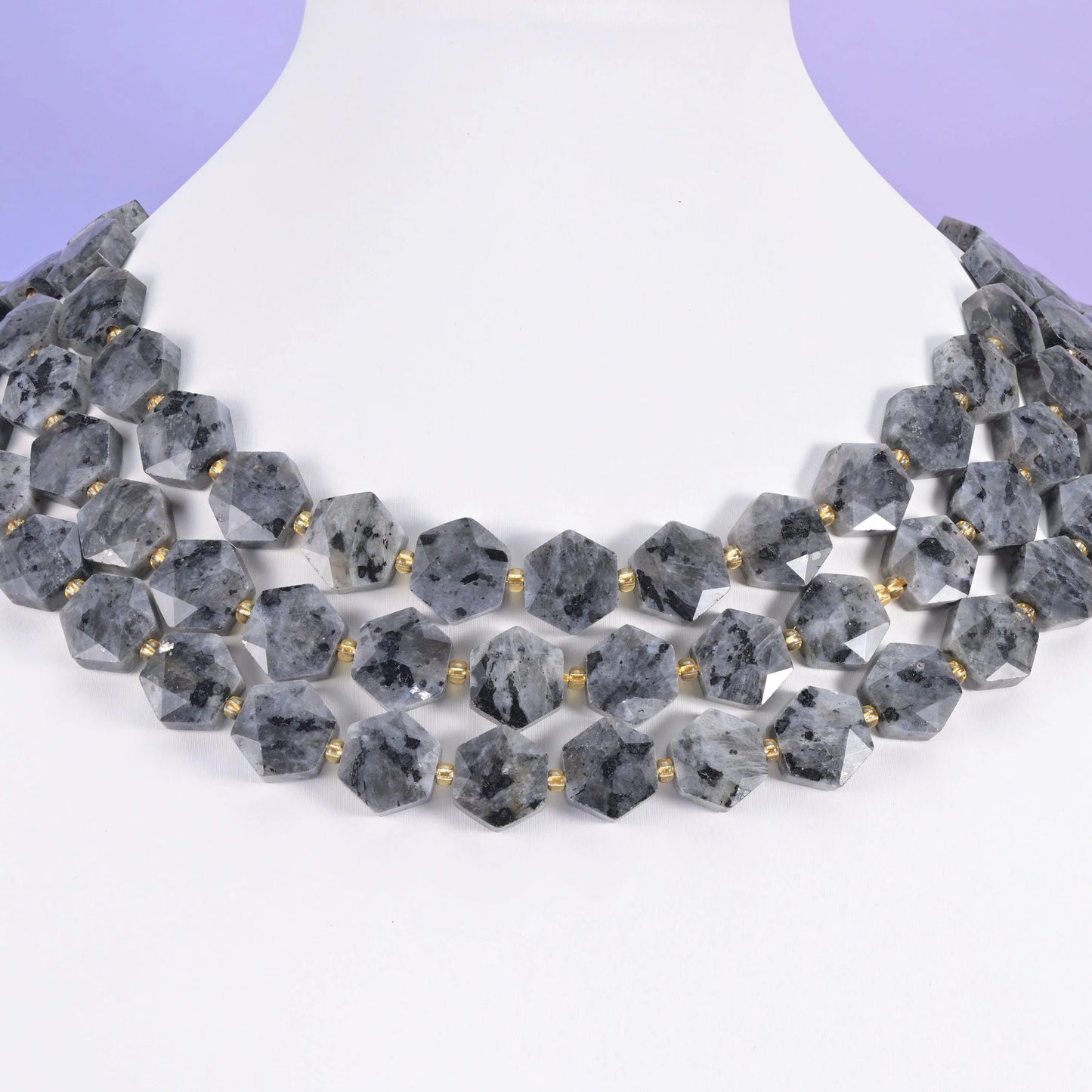 Grey Black Labradorite hexagon beads arranged across a white neck display form
