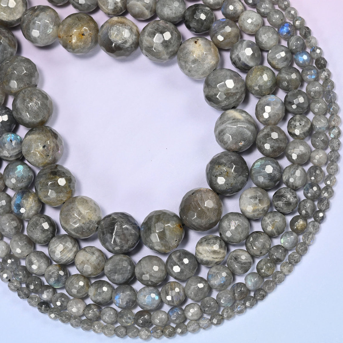 Gray Labradorite faceted round beads curved into a deep crescent, blue flash catching where the beads turn toward the light