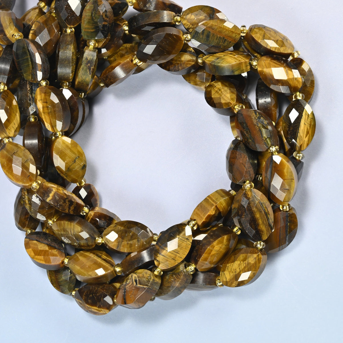 Tiger eye faceted flat oval beads coiled into overlapping loops, whole strands of golden brown stone