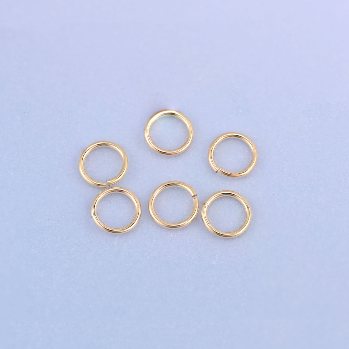Six 14K gold filled open jump rings in two staggered rows, a close view of the warm gold color and the smooth, tarnish-resistant surface.
