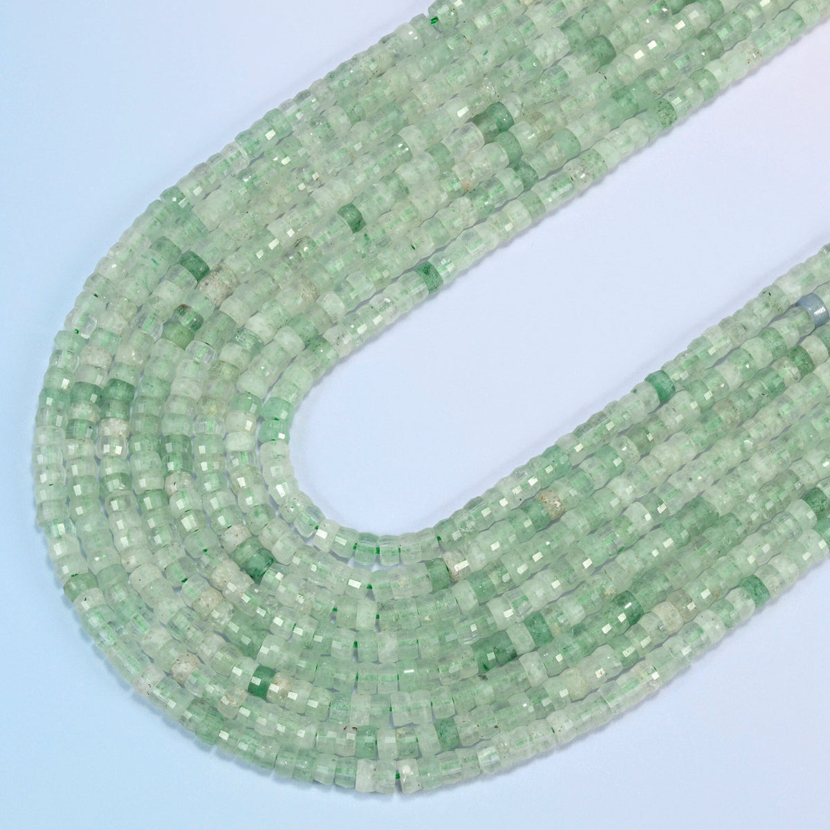 Green strawberry quartz faceted heishi disc beads in several strands curved into a wide U, light translucent green stone