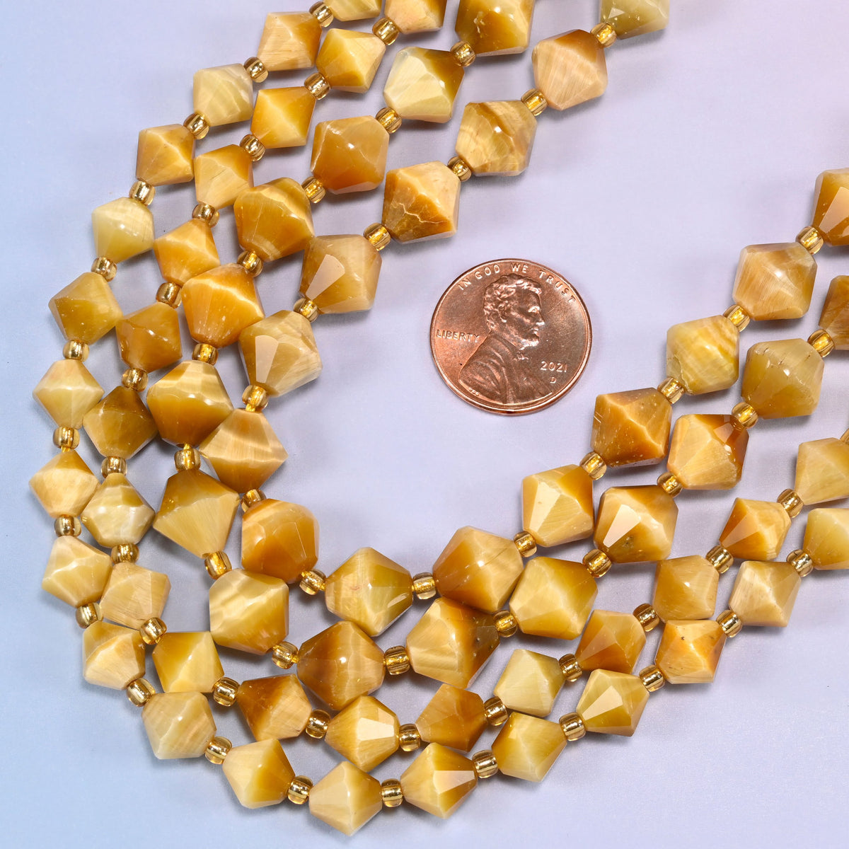 Gold tiger eye bicone beads in a wide curve, available in 8mm and 10mm, with a gold-tone spacer between each bead.