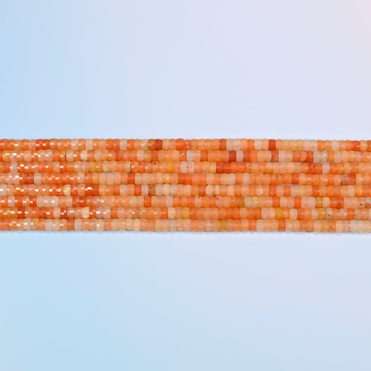 Several strands of red aventurine faceted heishi disc beads laid in straight rows