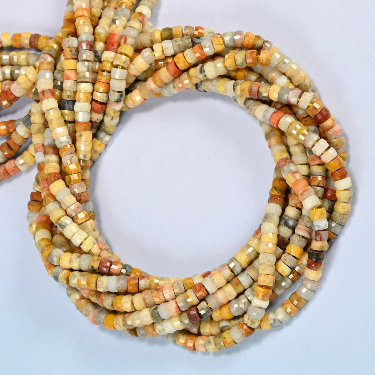 Crazy agate faceted heishi disc beads coiled into overlapping loops, whole strands of warm multicolor stone