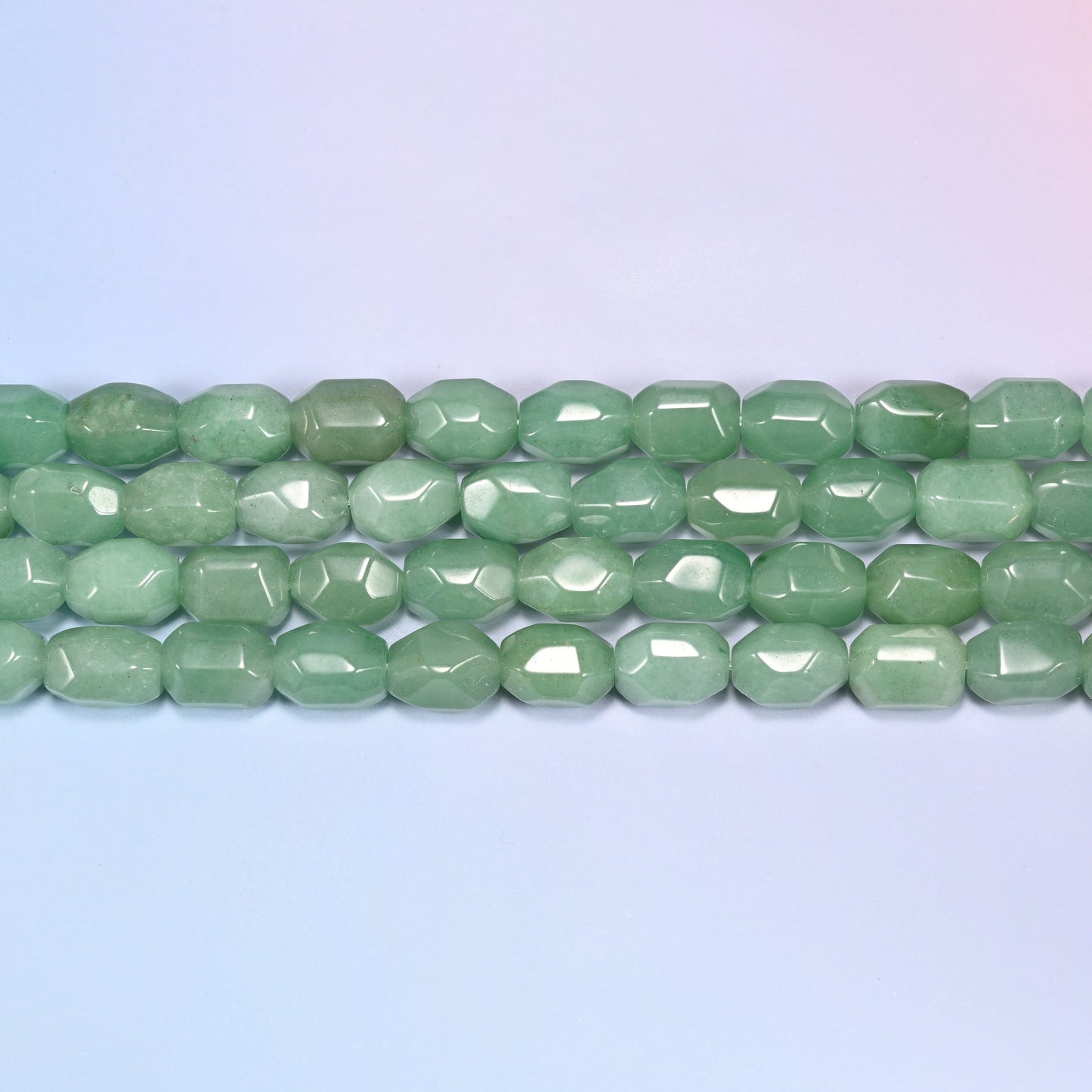 Close-up rows of green faceted Aventurine barrel beads laid diagonally, showing the sage green color variation and facet cuts.