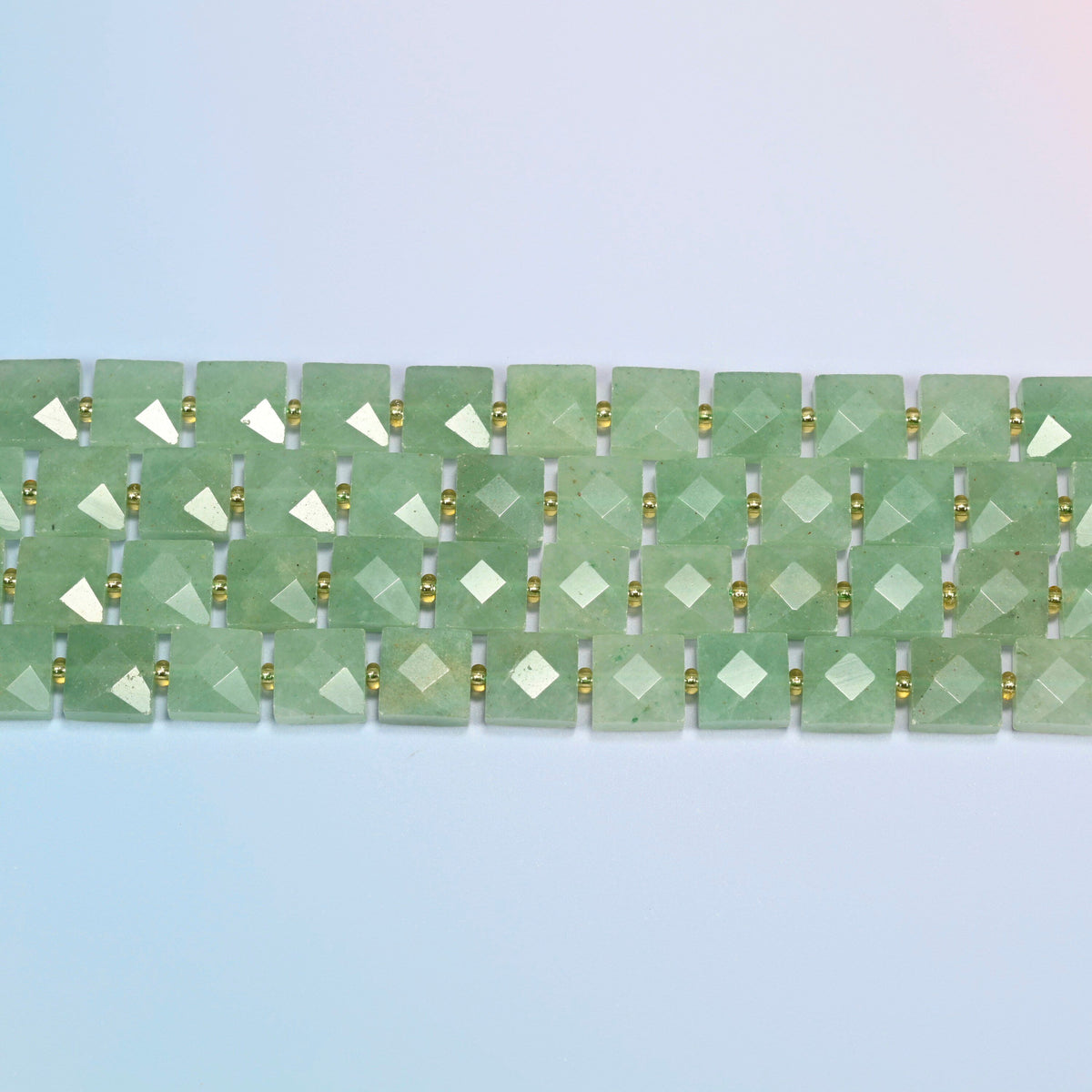 Several strands of natural green aventurine faceted flat square beads laid in straight rows