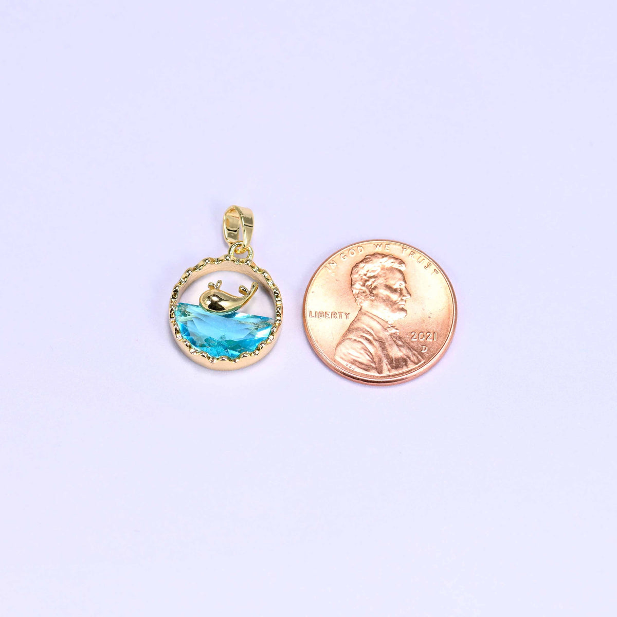 Whale charm with a gold whale silhouette diving into a faceted blue zirconia wave