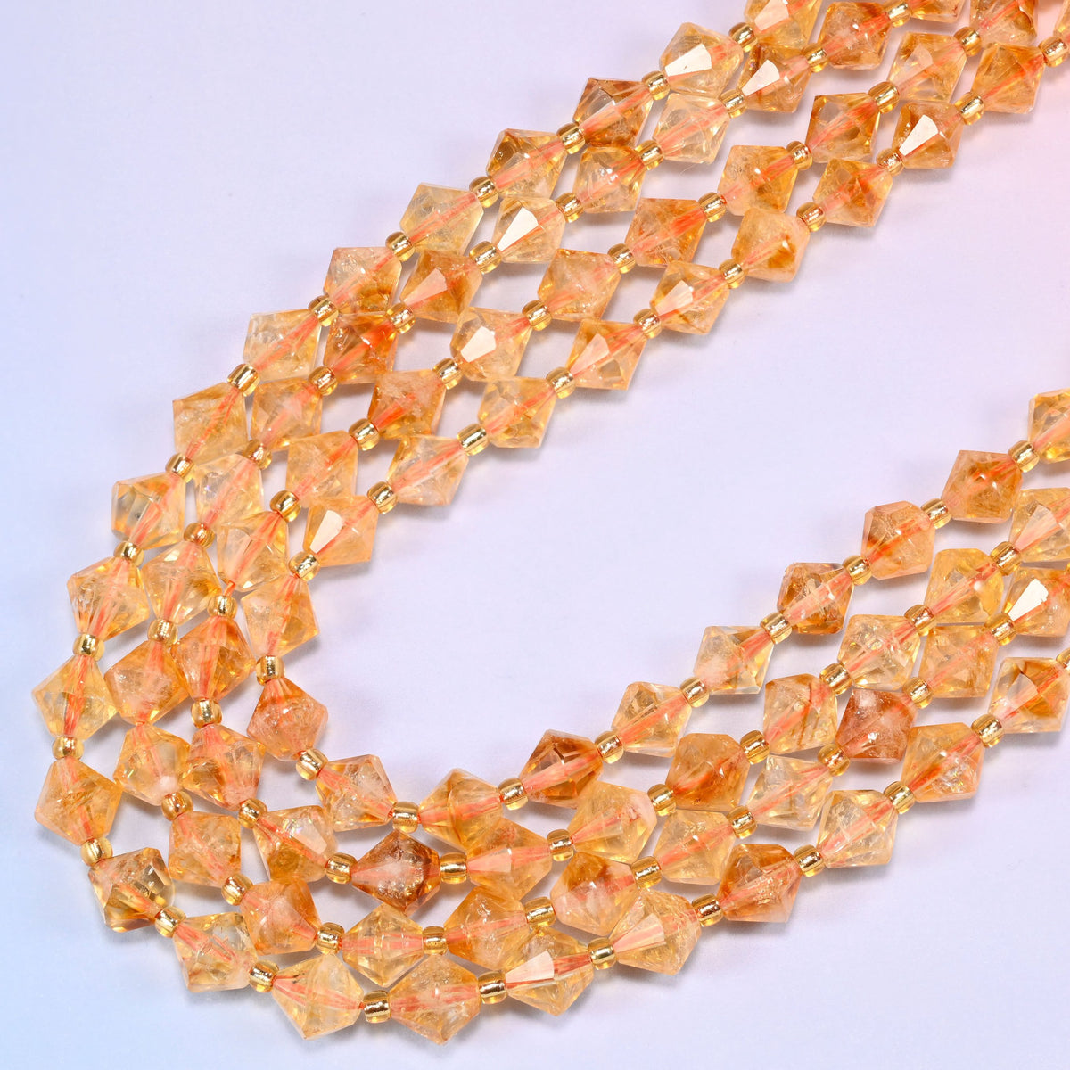 Citrine bicone beads in a wide loop curving down and back, the golden orange tone deepening in the thicker parts of each bead.