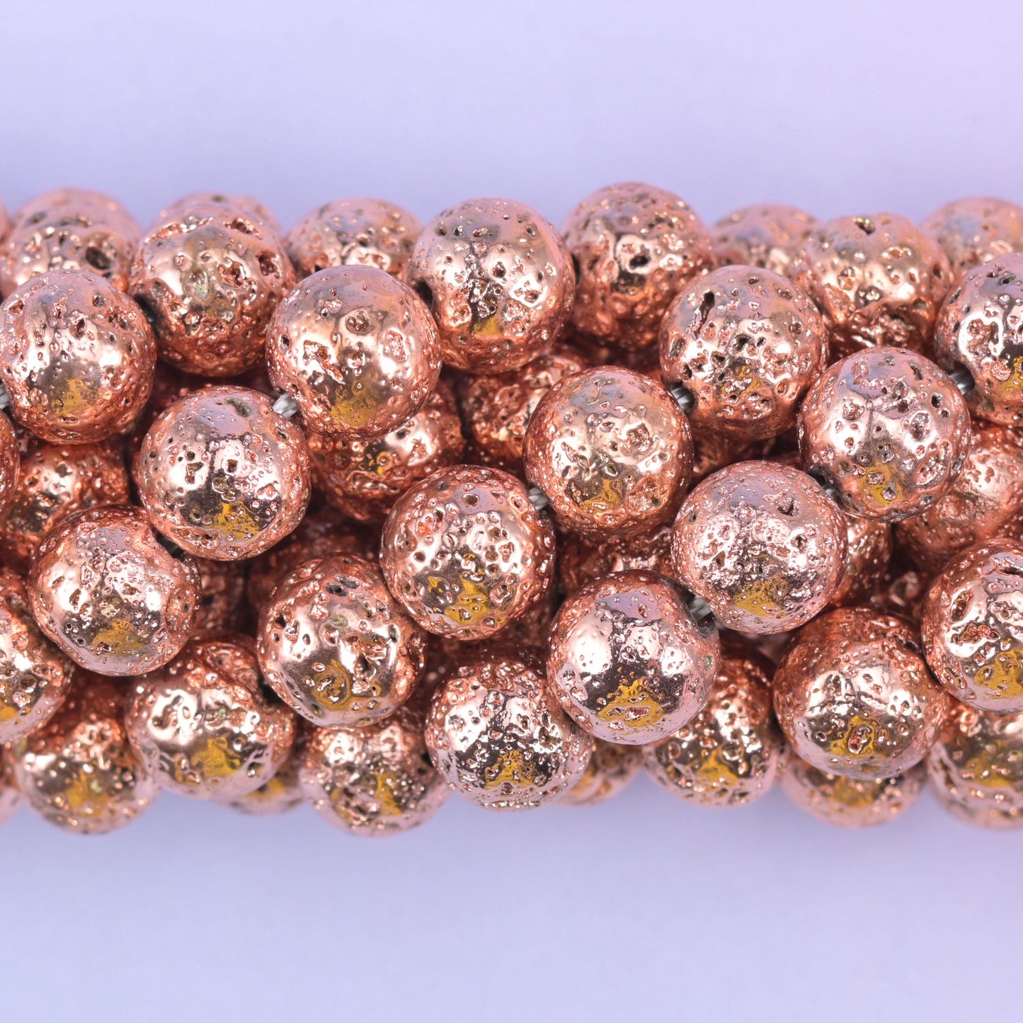 Round cut volcano rock lava beads with a porous, rose gold coated surface