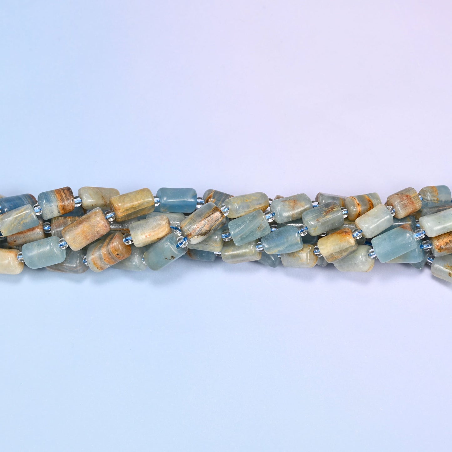 Close-up of coiled Blue Calcite tube beads with clear glass spacers, showing the natural stone texture and color variation.
