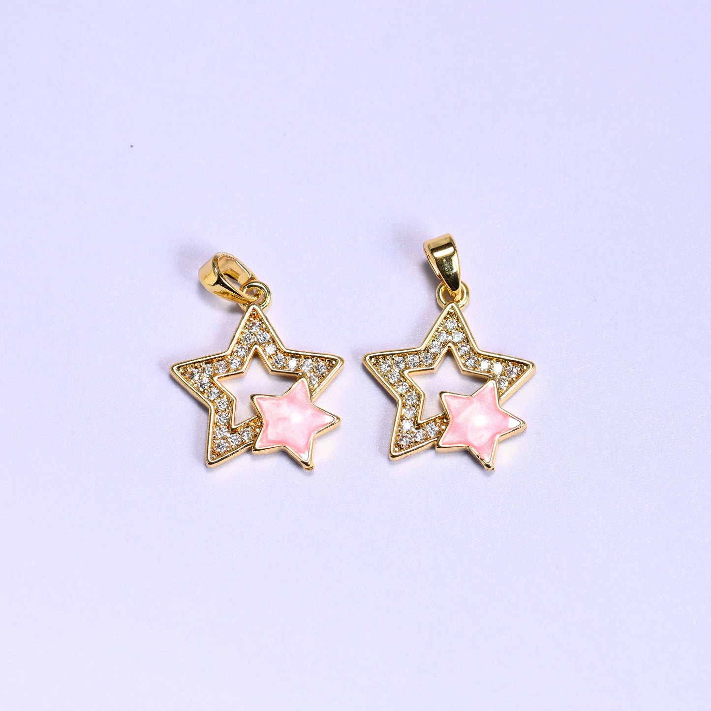 Two pink Double Stars Zirconia Charms side by side, each 18K gold plated with a zirconia pave outline star framing a soft pink shell inner star.