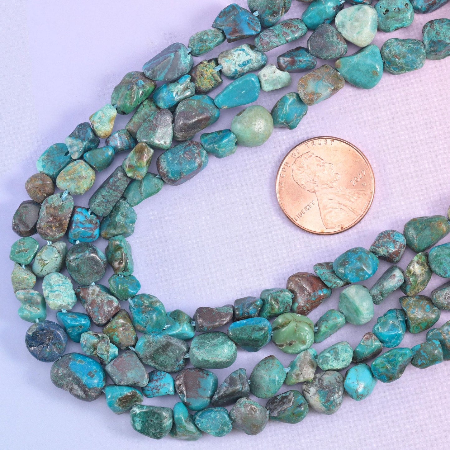 Strands looped beside a US penny, giving scale for the 6-8mm irregular nuggets