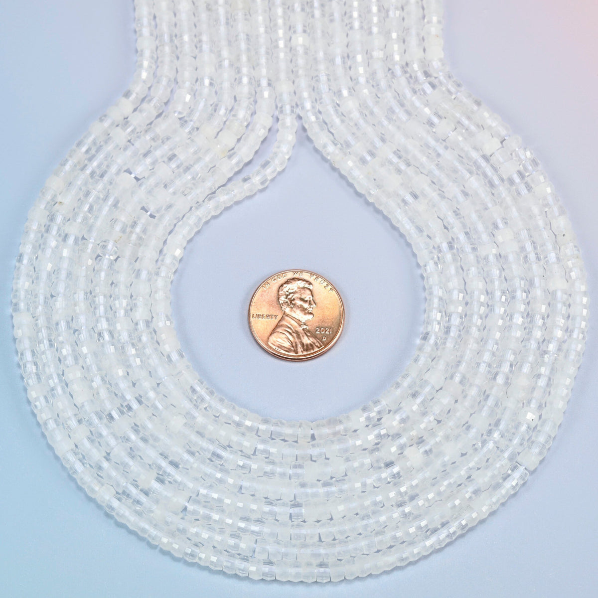 Clear quartz faceted heishi disc strands formed into a teardrop loop around a US penny for scale
