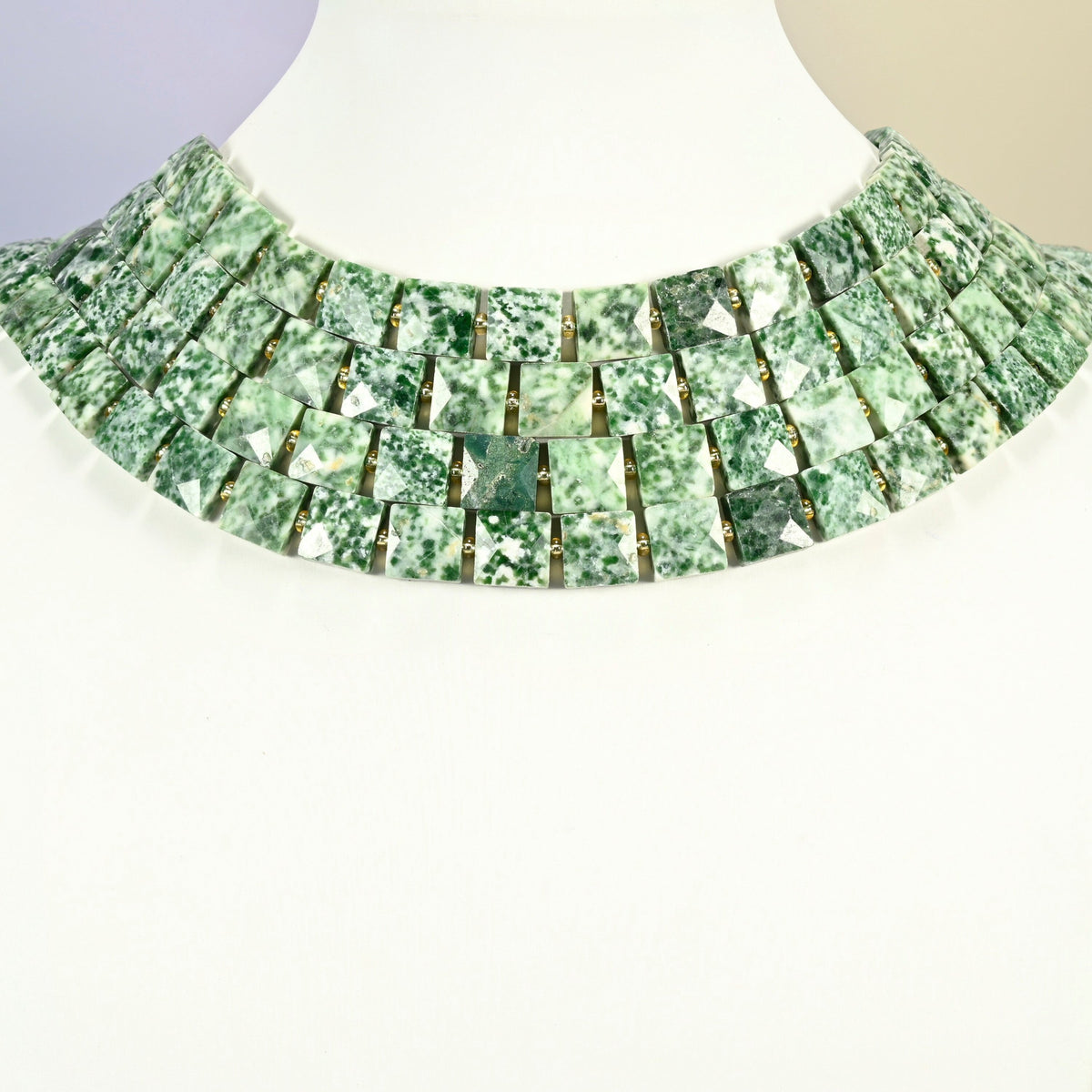 Tree agate faceted flat square strands arranged as a layered collar on a white display bust, green and white beads across the neck