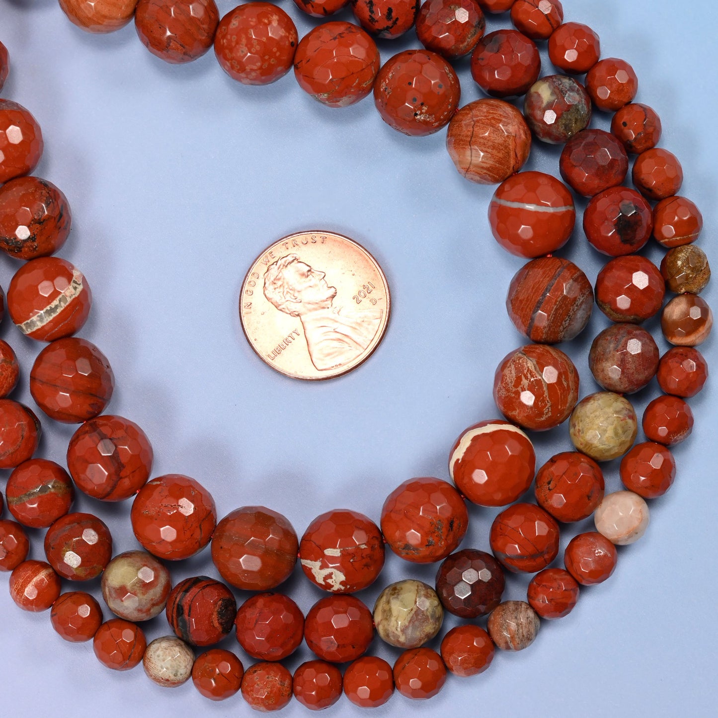 Group of flower red jasper round beads showing natural color and pattern variation.