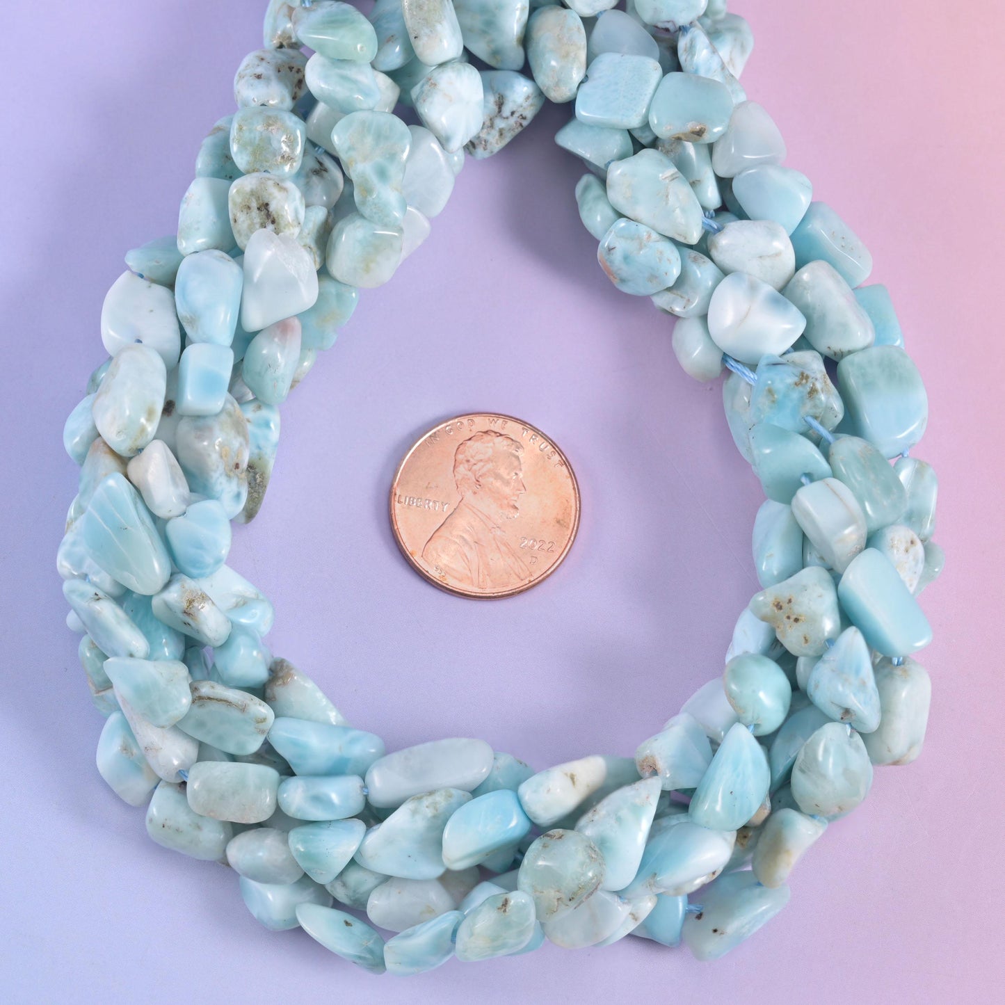 Open loop of larimar nuggets around a penny, the pale blue reading almost white in places