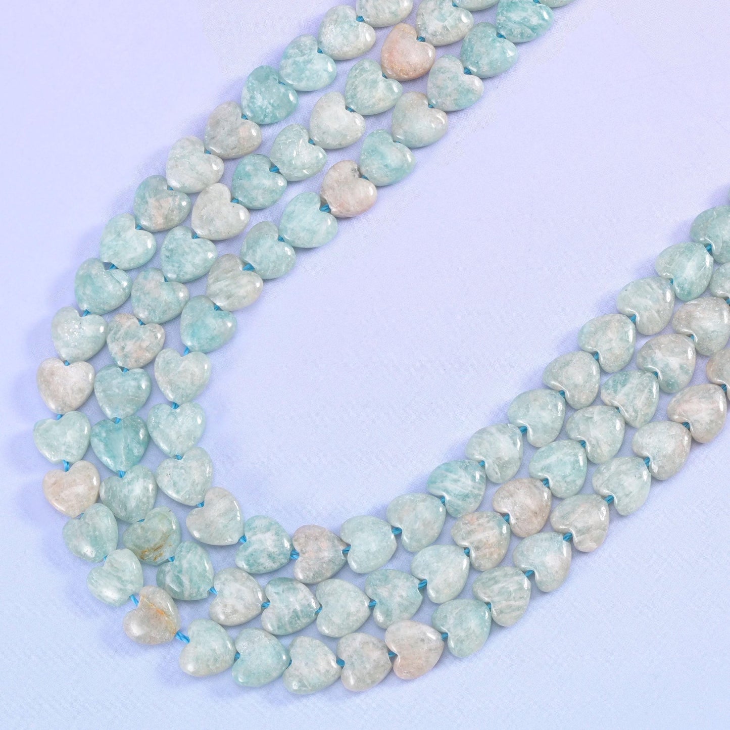 Blue Amazonite heart strands curving in a wide U on a lilac background