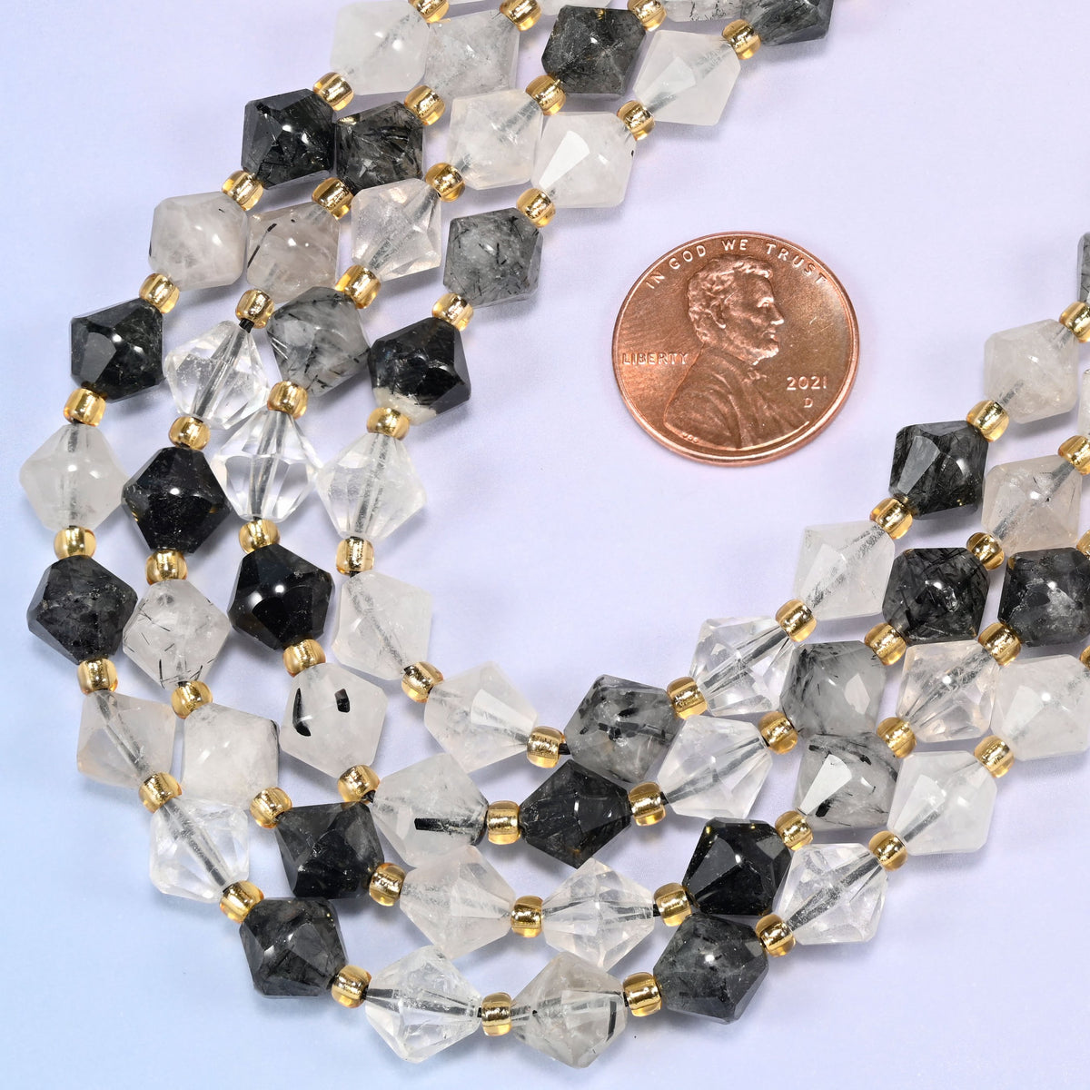 Black rutilated quartz bicone beads in a wide curve, 8mm beads with a gold-tone spacer between each one.
