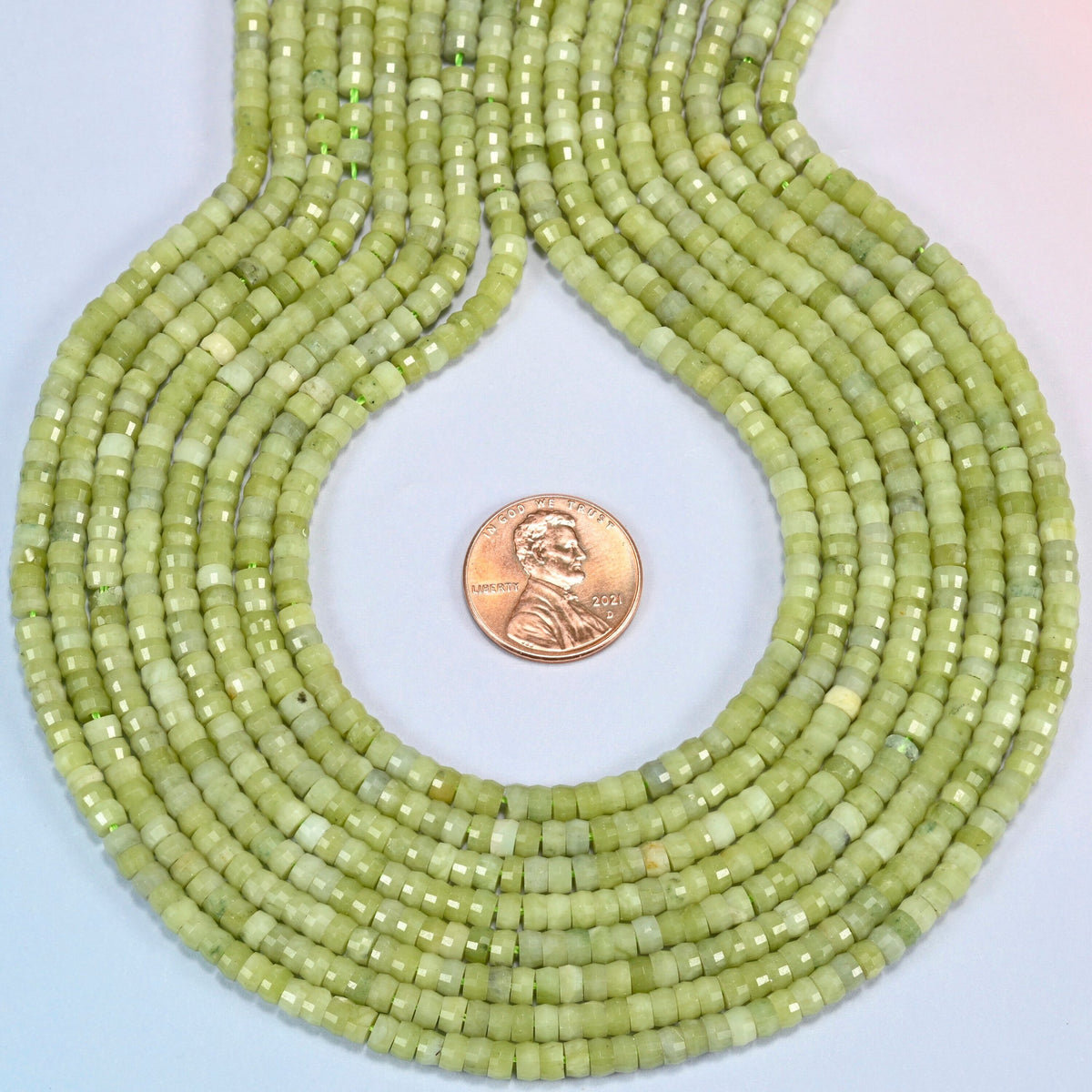 South Jade faceted heishi disc strands formed into a teardrop loop around a US penny for scale