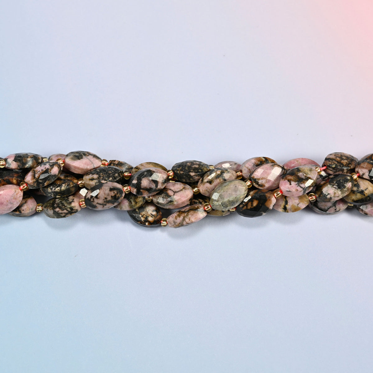 Strands of rhodonite faceted flat oval beads twisted together in a horizontal row