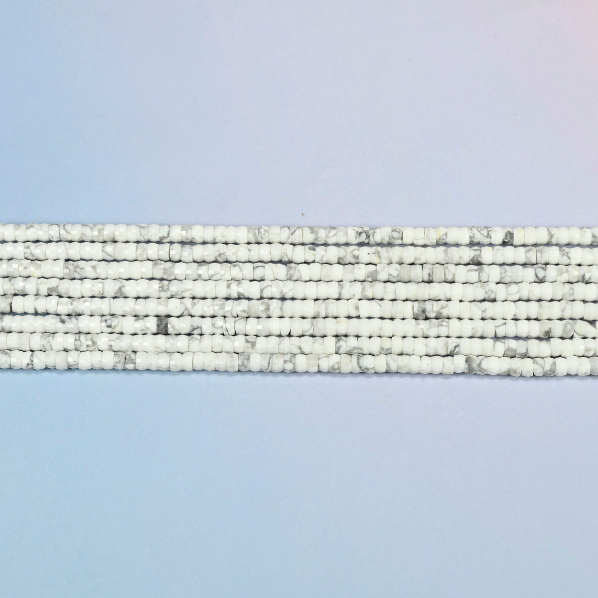 Several strands of white howlite faceted heishi disc beads laid in straight rows