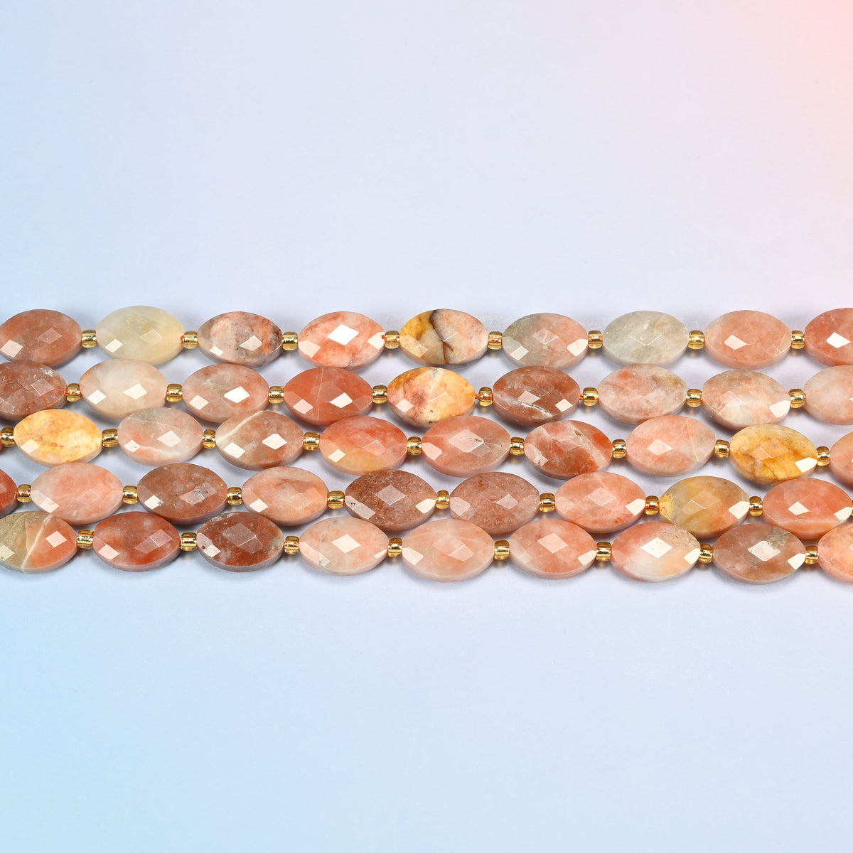 Several strands of red crazy agate faceted flat oval beads laid in straight rows with gold seed bead spacers