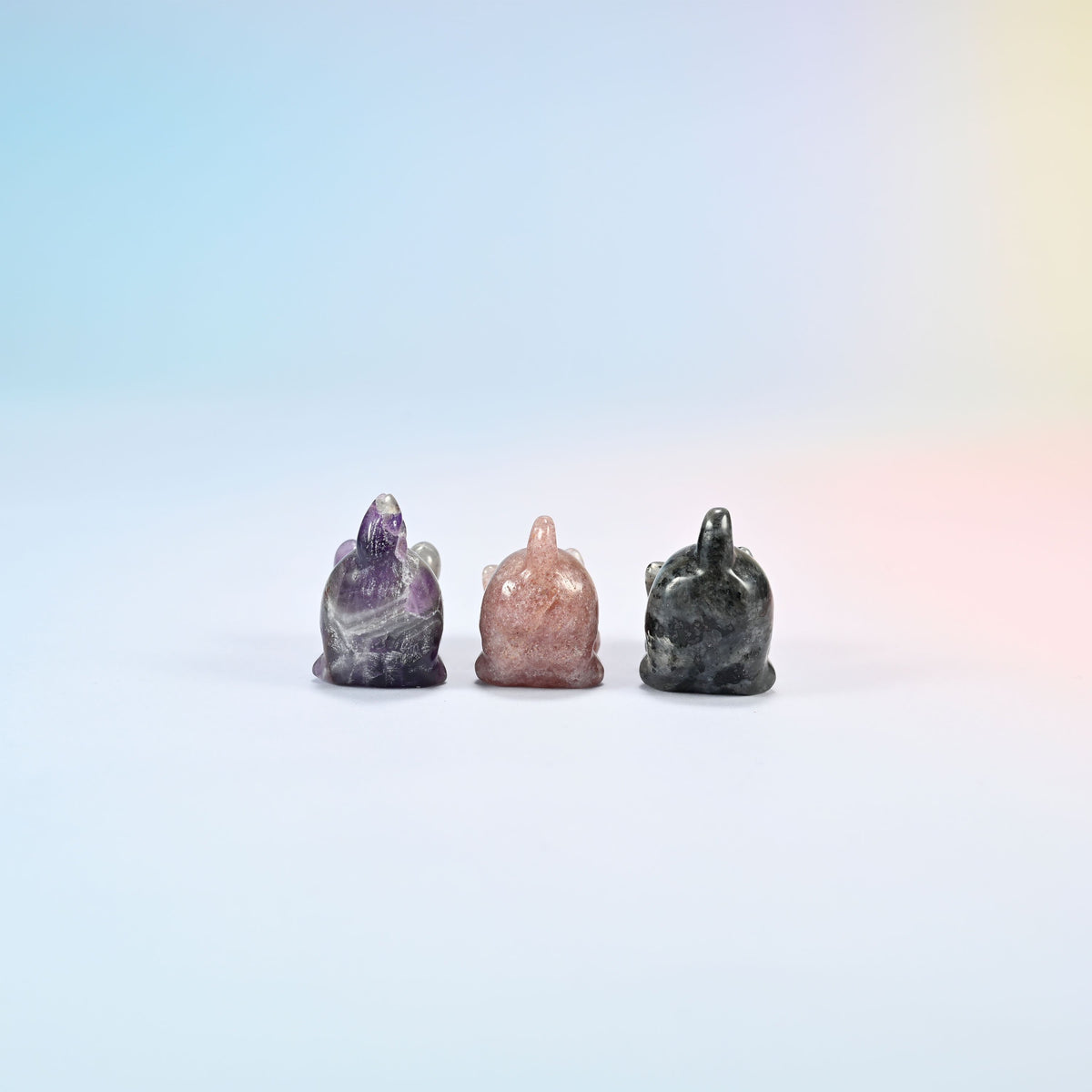 Back view of natural amethyst, strawberry quartz and black labradorite yoga cat carvings showing their raised tails
