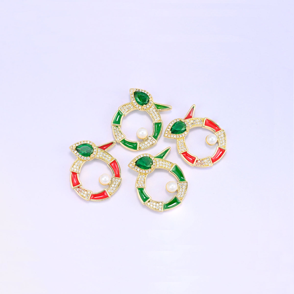 Four round snake charms grouped at an angle, two green and two red enamel pieces with pave zircon, pear cut green stones and pearl centres.