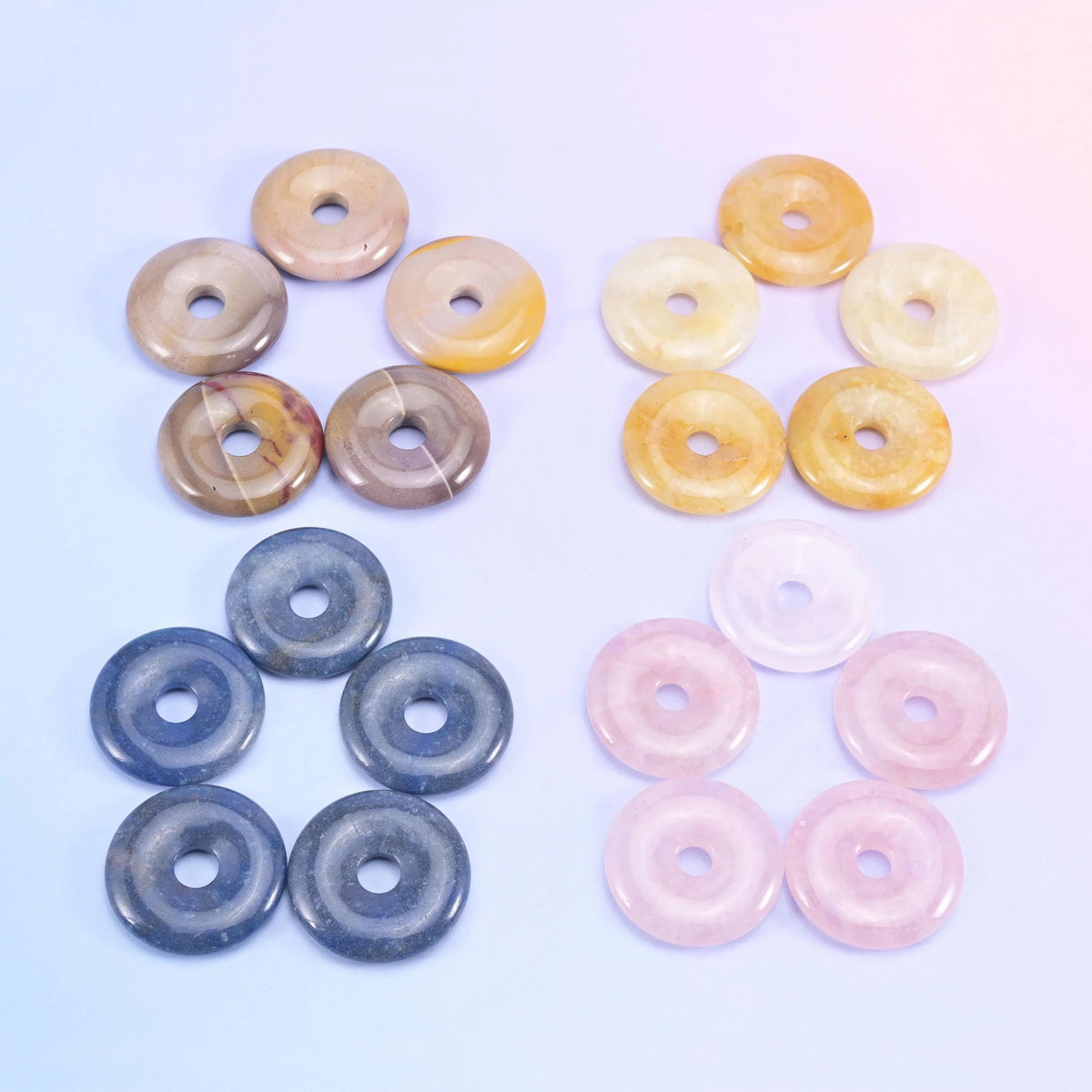 Cream, yellow, navy blue and pale pink donuts laid out in four groups