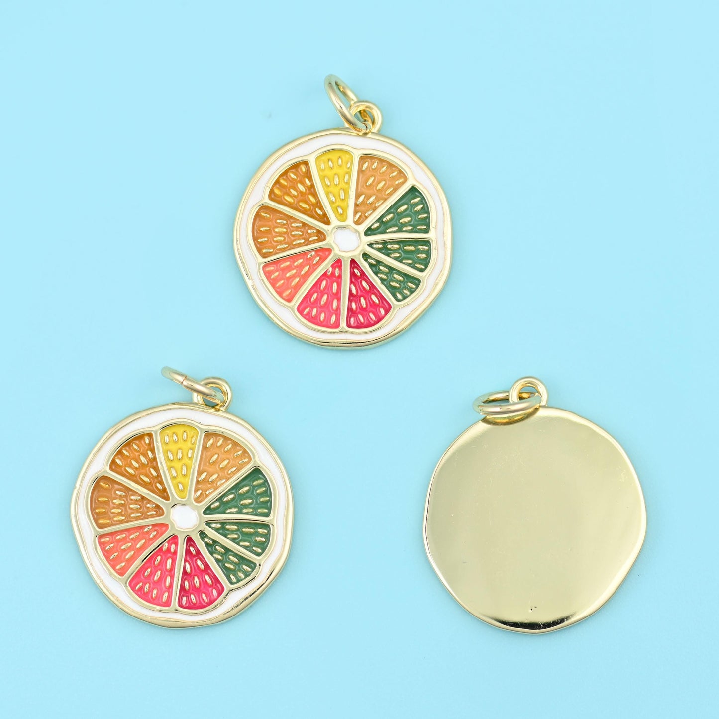 A citrus slice cut into six enamelled wedges in yellow, orange, coral, pink and two shades of green, ringed by a pale cream…