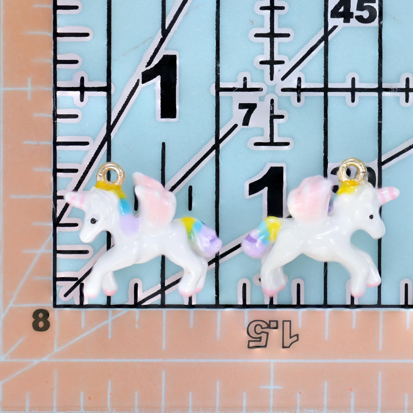 A prancing unicorn moulded in glossy white enamel with a pastel pink and lilac mane and tail, pale hooves and a small gold horn
