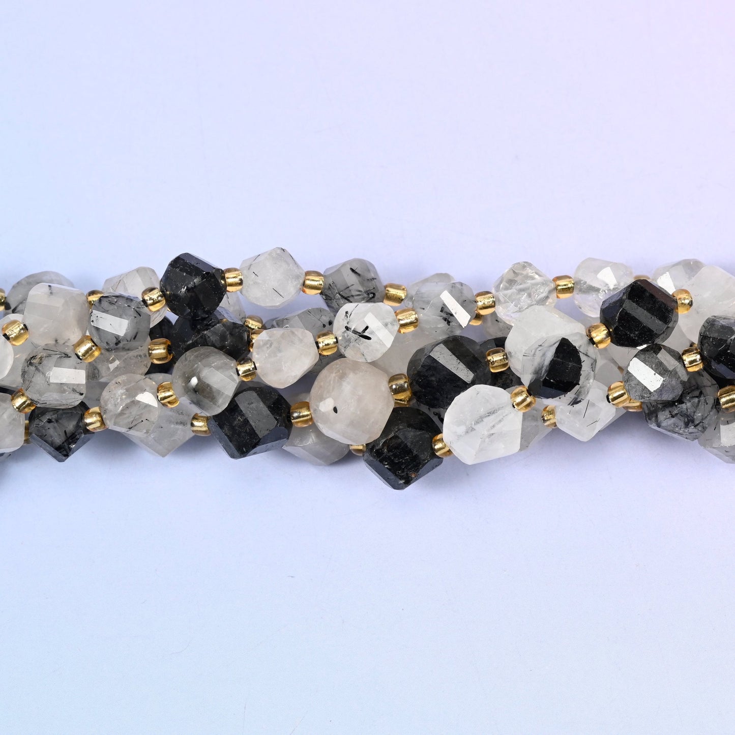 Clear to snowy white quartz shot through with jet-black tourmaline needles, running from beads with only a few fine dark threads to beads that are almost solid black