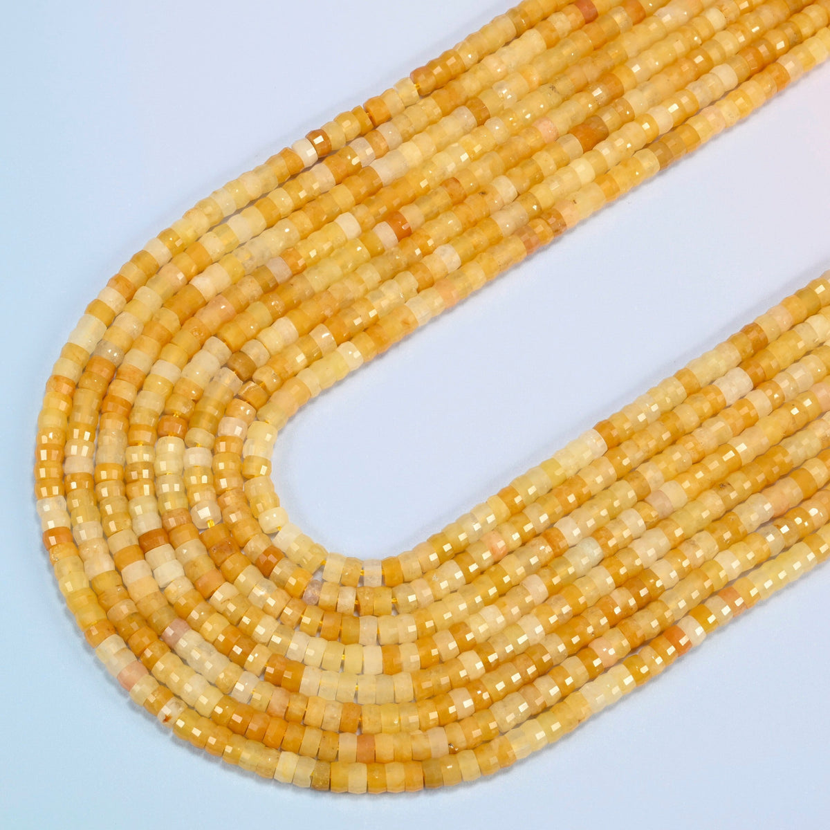 Gold Silk Jade faceted heishi disc beads in several strands curved into a wide U, golden yellow and honey stone