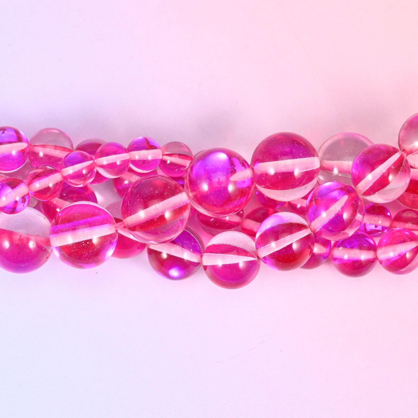 Transparent raspberry-pink glass beads finished with an iridescent aura coating