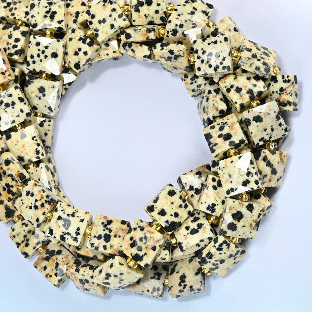 Dalmatian jasper faceted flat square beads coiled into overlapping loops, whole strands of black-spotted cream stone
