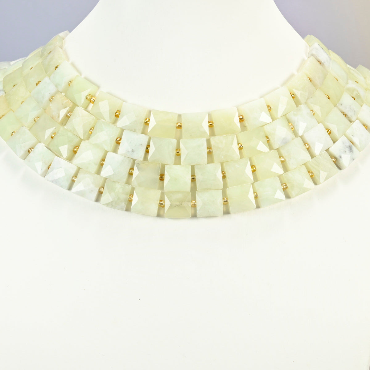 New Jade faceted flat square strands arranged as a layered collar on a white display bust, light yellow-green beads across the neck