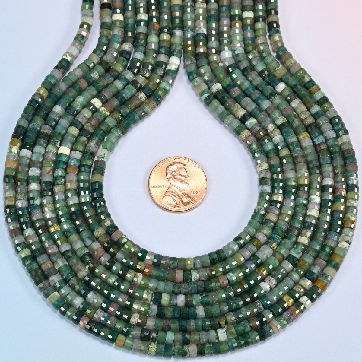 Indian agate faceted heishi disc strands formed into a teardrop loop around a US penny for scale