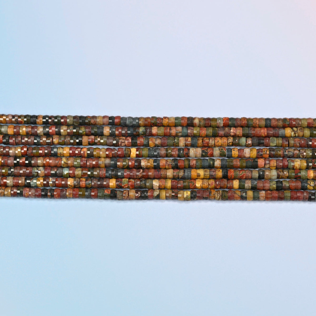 Several strands of red howlite faceted heishi disc beads laid in straight rows