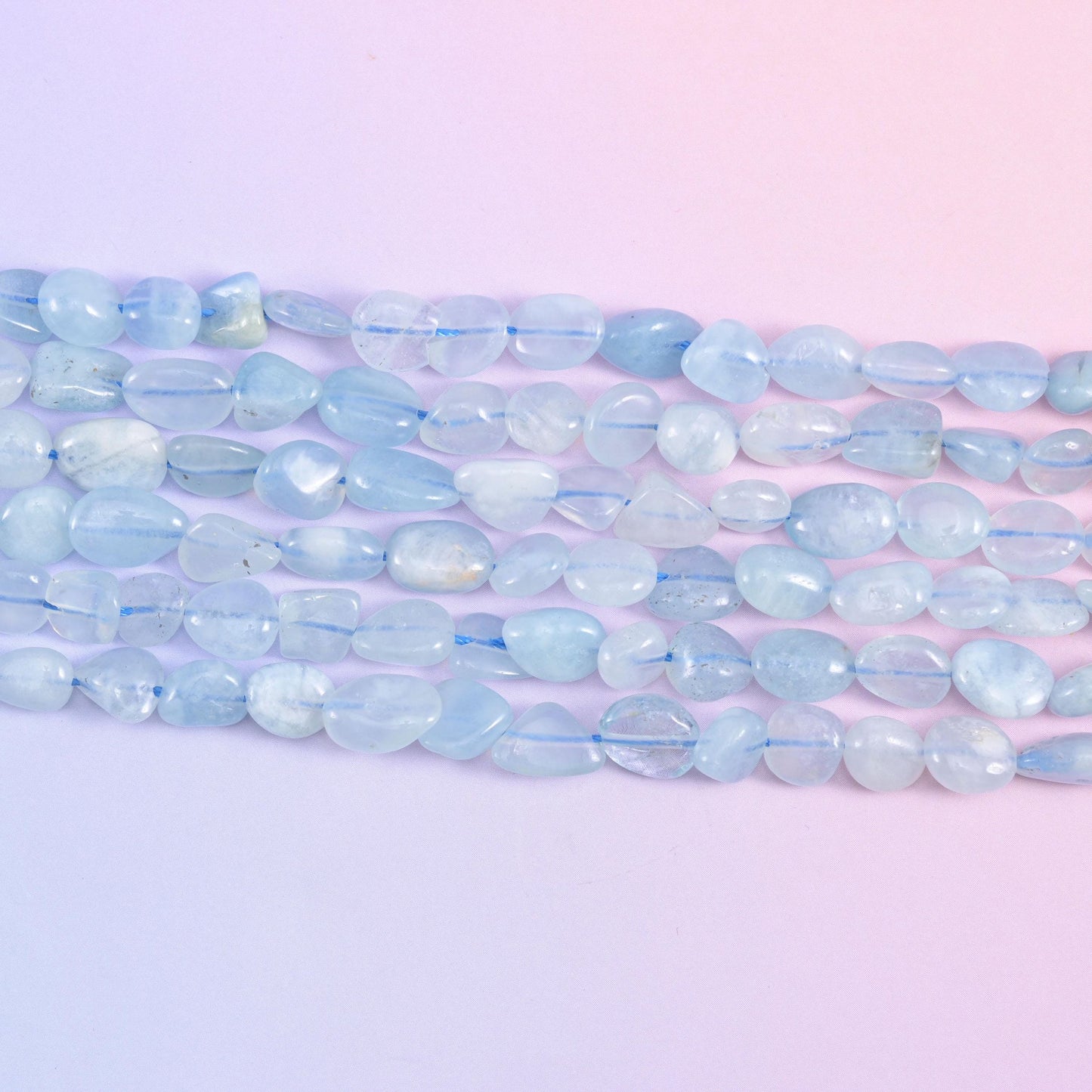 Close row of smooth polished aquamarine nuggets in milky sky blue and white