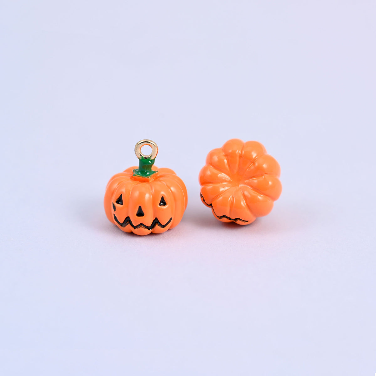 Enamel pumpkin charms with one turned to show the ribbed cap and green enamel stem around the gold-tone ring.