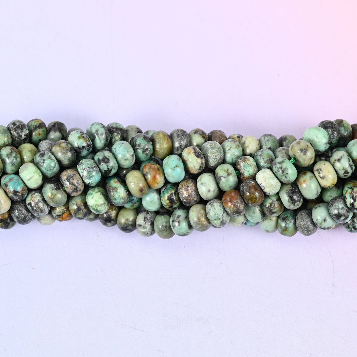 Mottled green shot through with bold black matrix veining — turquoise's quieter cousin — polished to a clean shine and cut as a smooth rondelle in two sizes.
