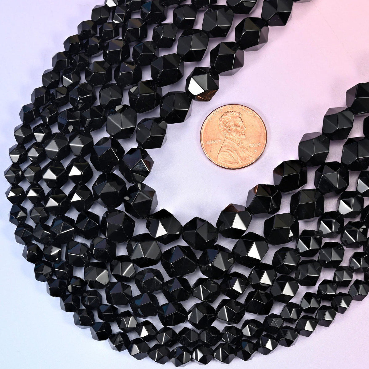 Black Onyx star cut beads with a US penny alongside for size reference, available in 6mm, 8mm and 10mm