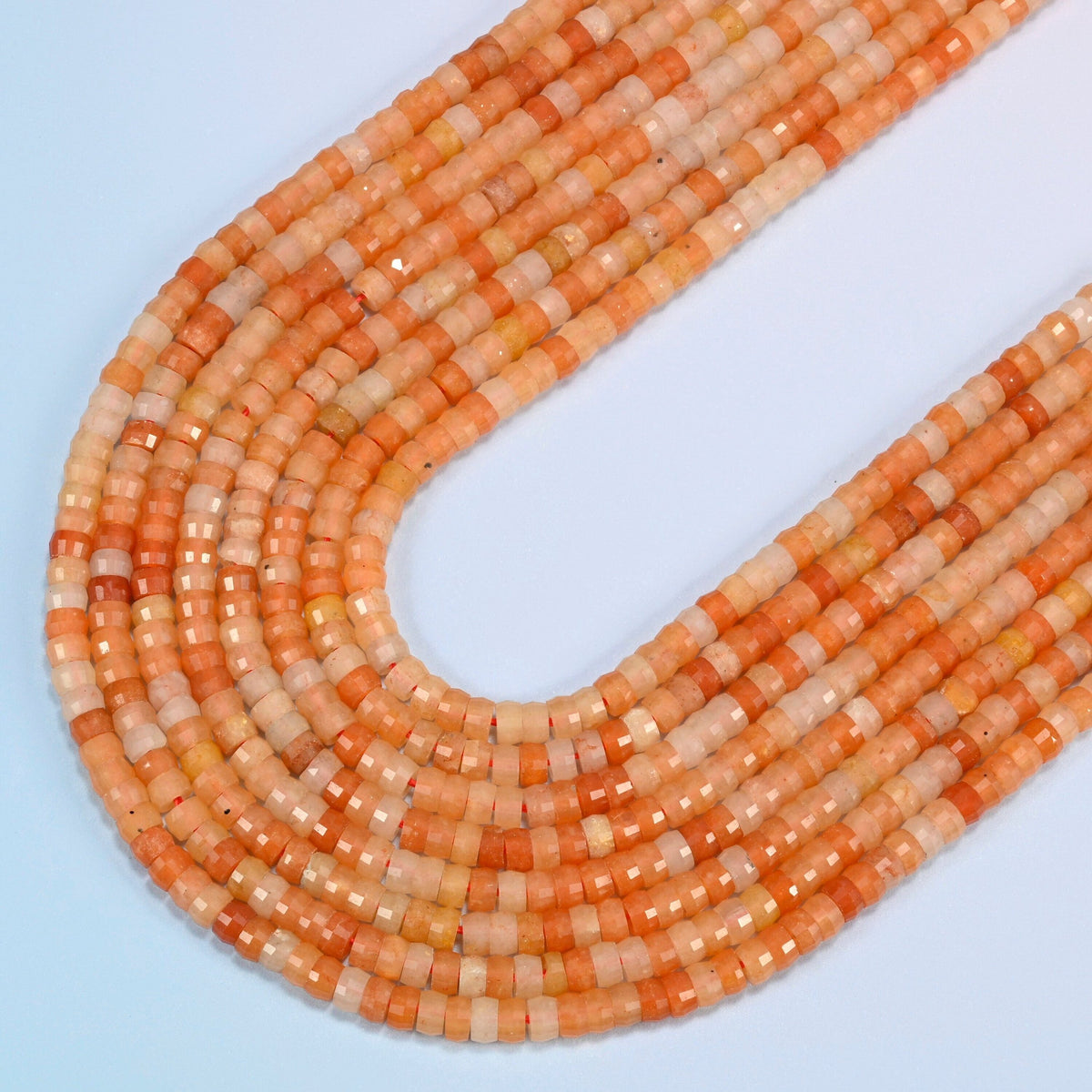 Red aventurine faceted heishi disc beads in several strands curved into a wide U, orange-red and peach orange stone