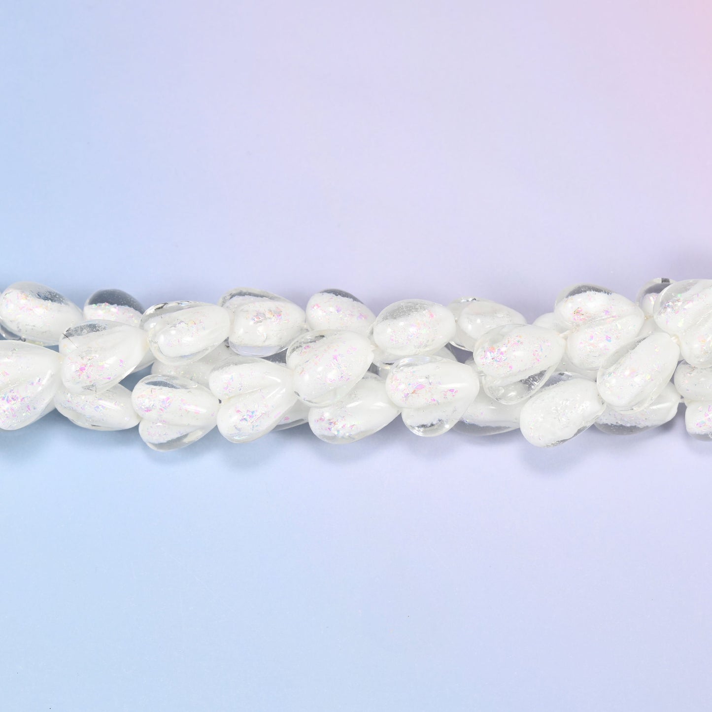 Milky opaque white glass hearts carrying a soft pearly iridescence, closer to freshwater pearl than plain white glass