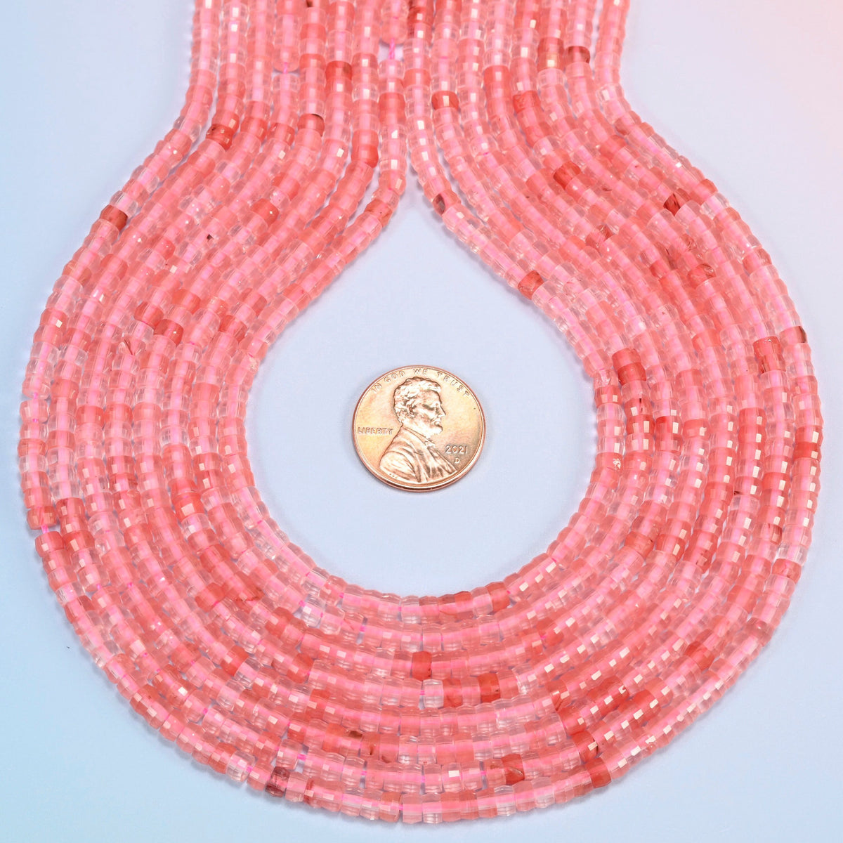 Melon quartz faceted heishi disc strands formed into a teardrop loop around a US penny for scale