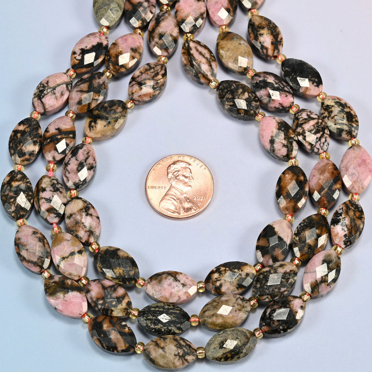 Rhodonite faceted flat oval strands formed into a teardrop loop around a US penny for scale