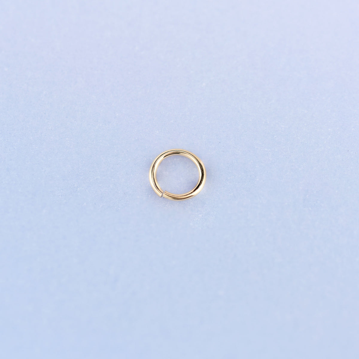 A single 14K gold filled open jump ring shown face on, 5mm across, with the split in the 22 gauge wire visible at the bottom.
