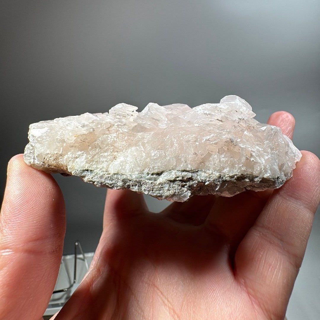 Side profile of the calcite plate held in fingers, showing its slim 36mm depth
