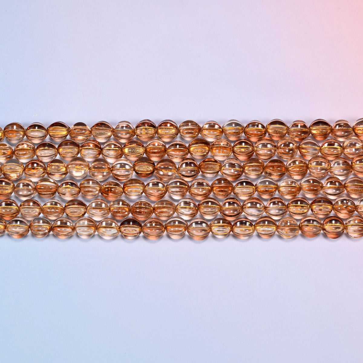 Close-up of 8mm brown pumpkin glass beads in four horizontal rows, showing the carved melon ribs.